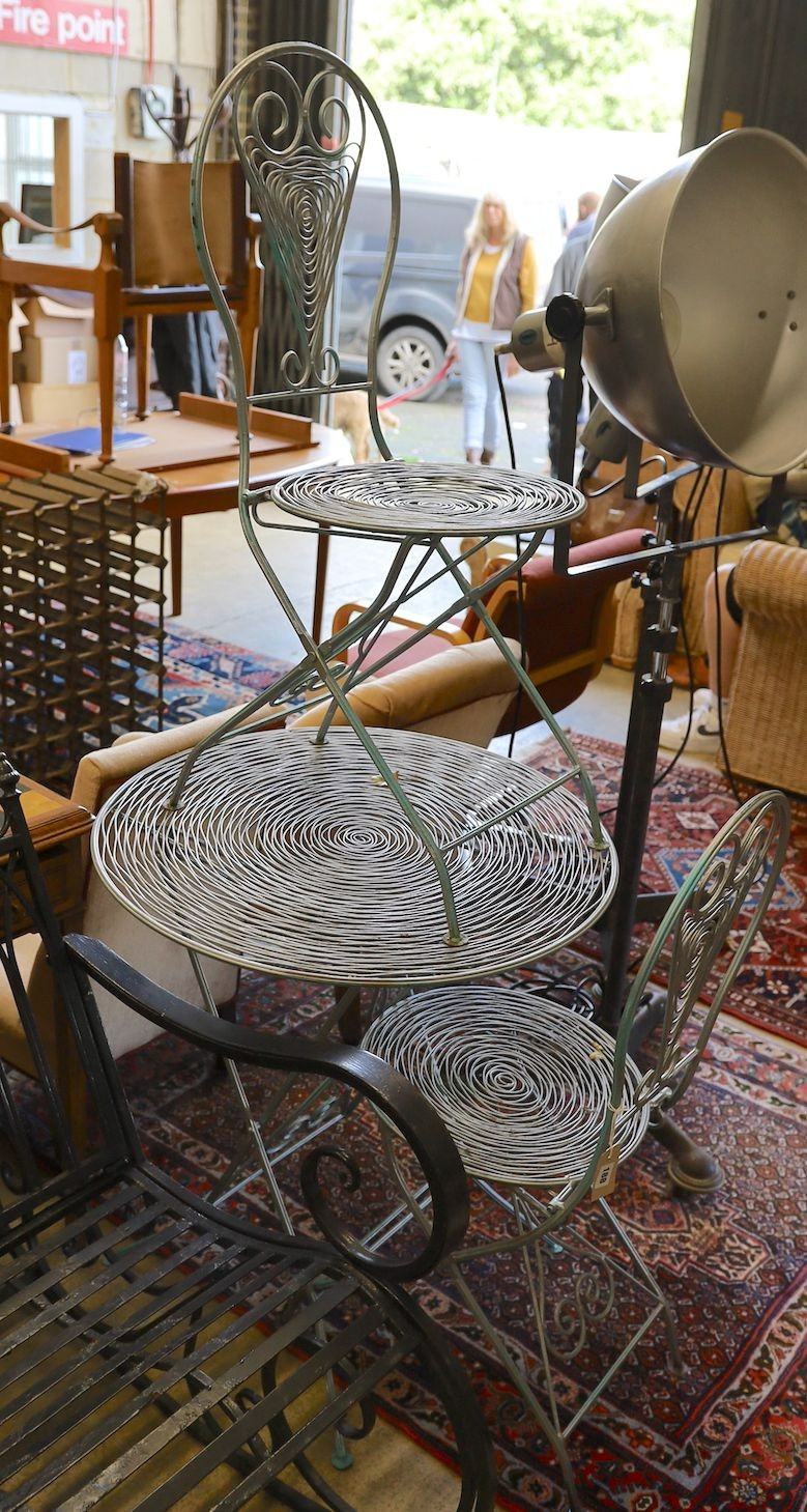 A painted wrought iron and wirework circular garden table, diameter 70cm, height 74m and two chairs